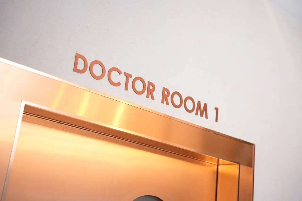 Copper DOCTOR ROOM 1 lettering above the copper-framed entrance to the doctor's examination room at The Cocktail Clinic, a GP clinic near BTS Phaya Thai, Bangkok