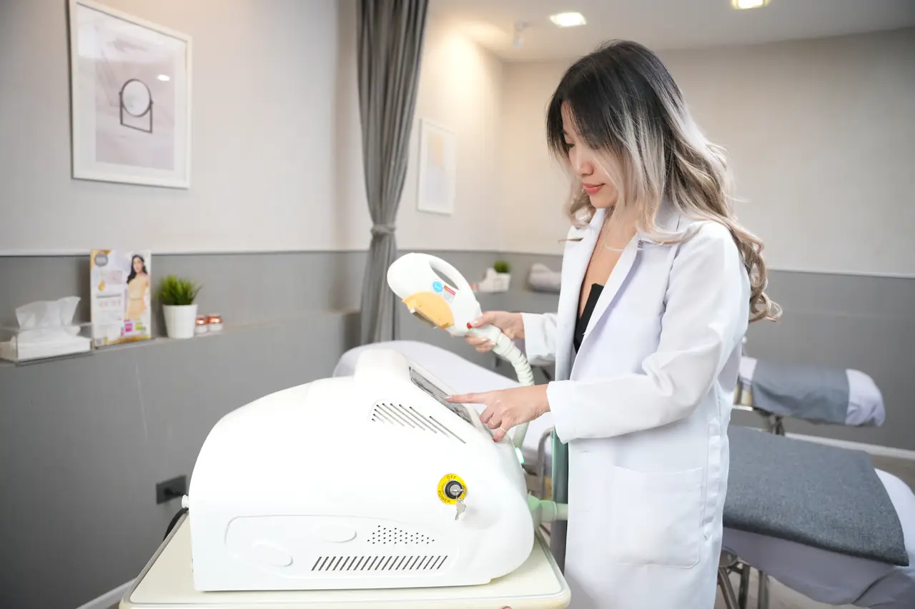 施術室のレーザー機器の横でハンドピースを持つ医師